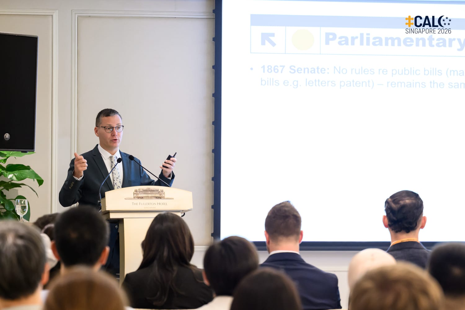 Mr Charlie Feldman presents on Canadian parliamentary printing requirements at the Conference, standing at the podium at The Fullerton Hotel Singapore.